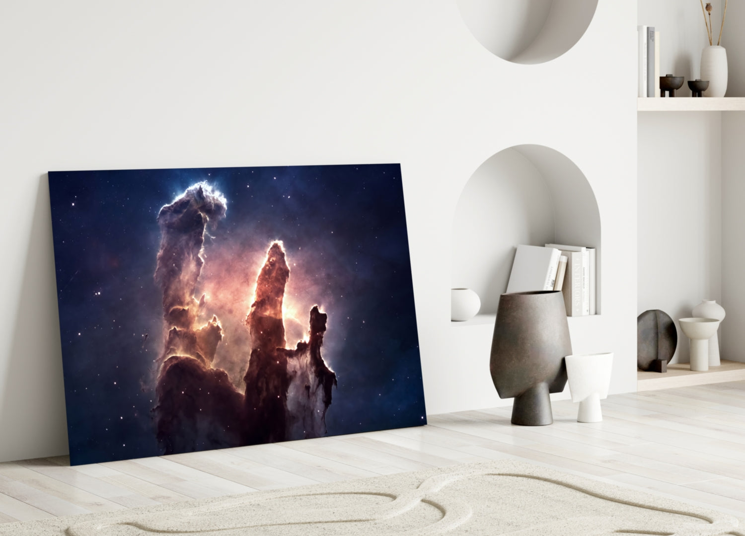 Space Clouds Glass Wall Art leaning against white wall in minimalist interior with sandy floor and decorative objects.