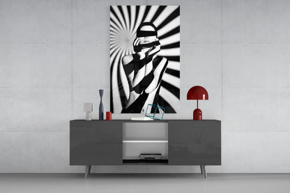 Black and white striped wall art featuring a blindfolded figure displayed above a gray media console with red decorative accessories.