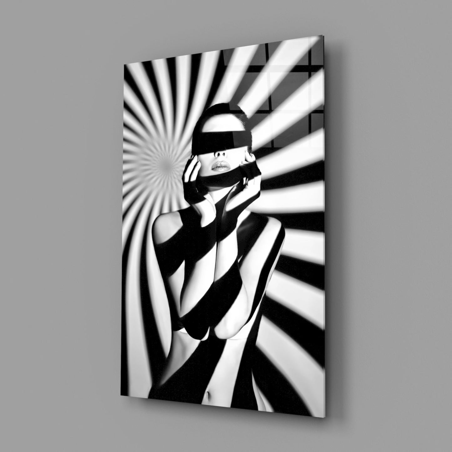 Black and white glass wall art showing a figure wearing headphones and eye covering against radiating striped background patterns.