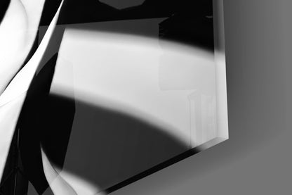 Abstract black and white glass wall art with geometric planes and dramatic shadows cast across white surface.
