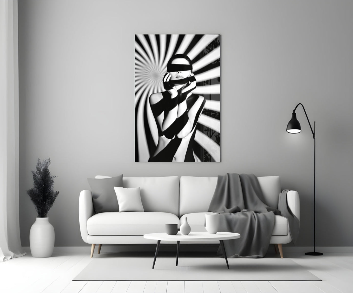 Black and white glass wall art depicting a censored figure with radiating stripes, displayed above a white sofa in a minimalist living room.