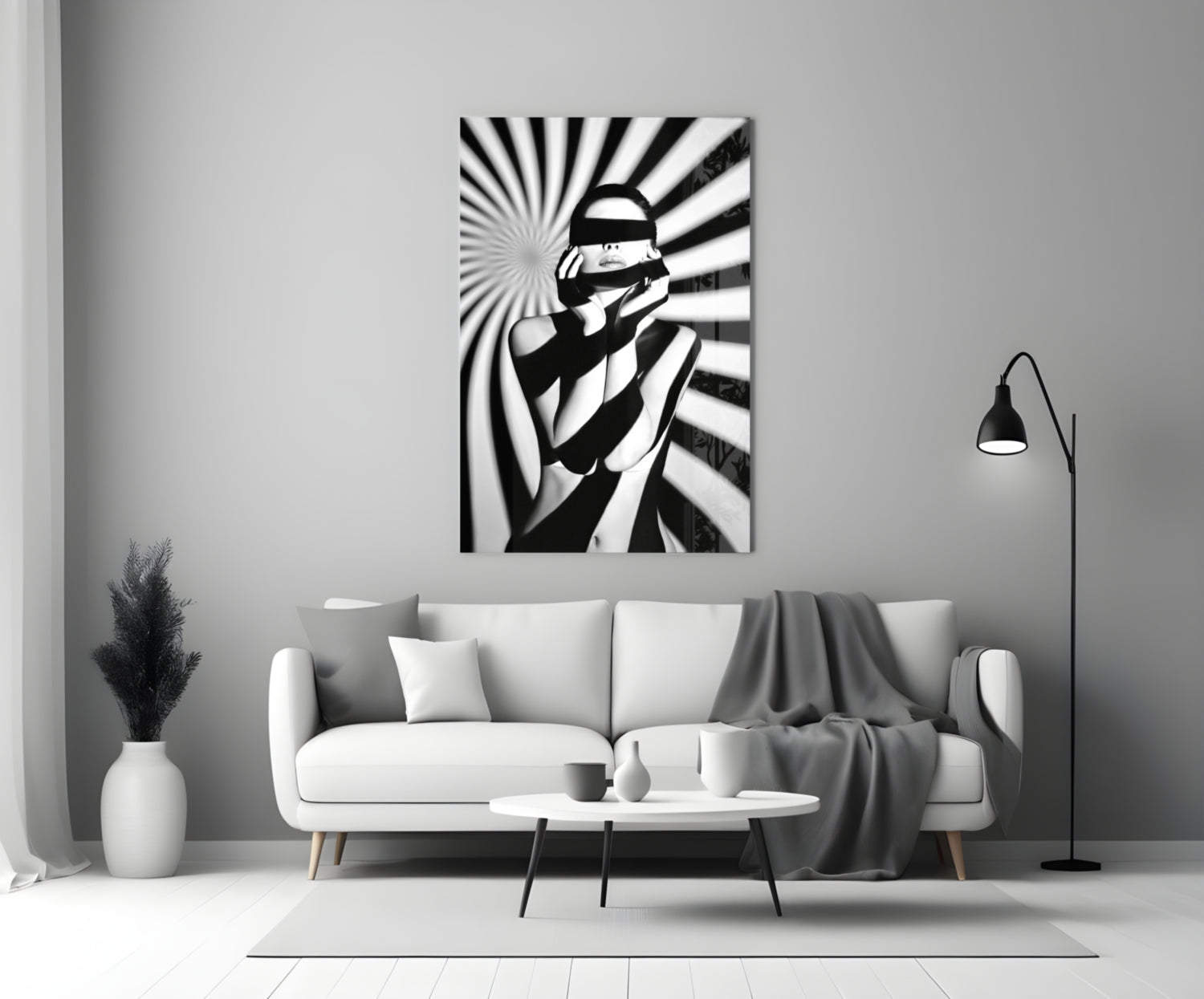 Black and white glass wall art depicting a censored figure with radiating stripes, displayed above a white sofa in a minimalist living room.