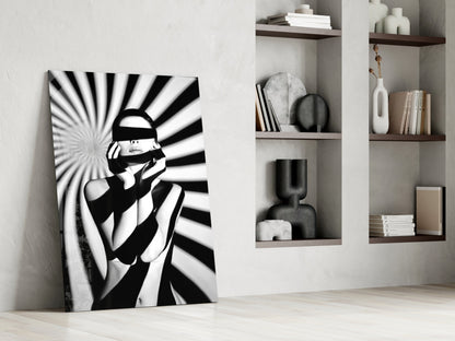 Black and white pop art glass panel leaning against white wall beside built-in shelving with decorative objects and books.