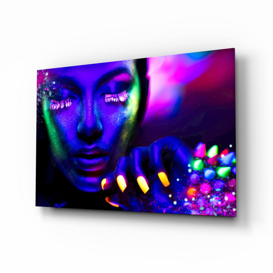 Angled perspective of glass wall art displaying a woman's face in neon purple, blue, and green body paint with glowing yellow nails and colorful spheres.