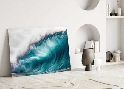 Wave Glass Wall Art leaning against white wall beside sculptural decor, displaying turquoise ocean wave with white foam.