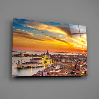 Glass wall art displaying Venice at sunset with illuminated basilica, waterfront buildings, and golden sky reflected in water.