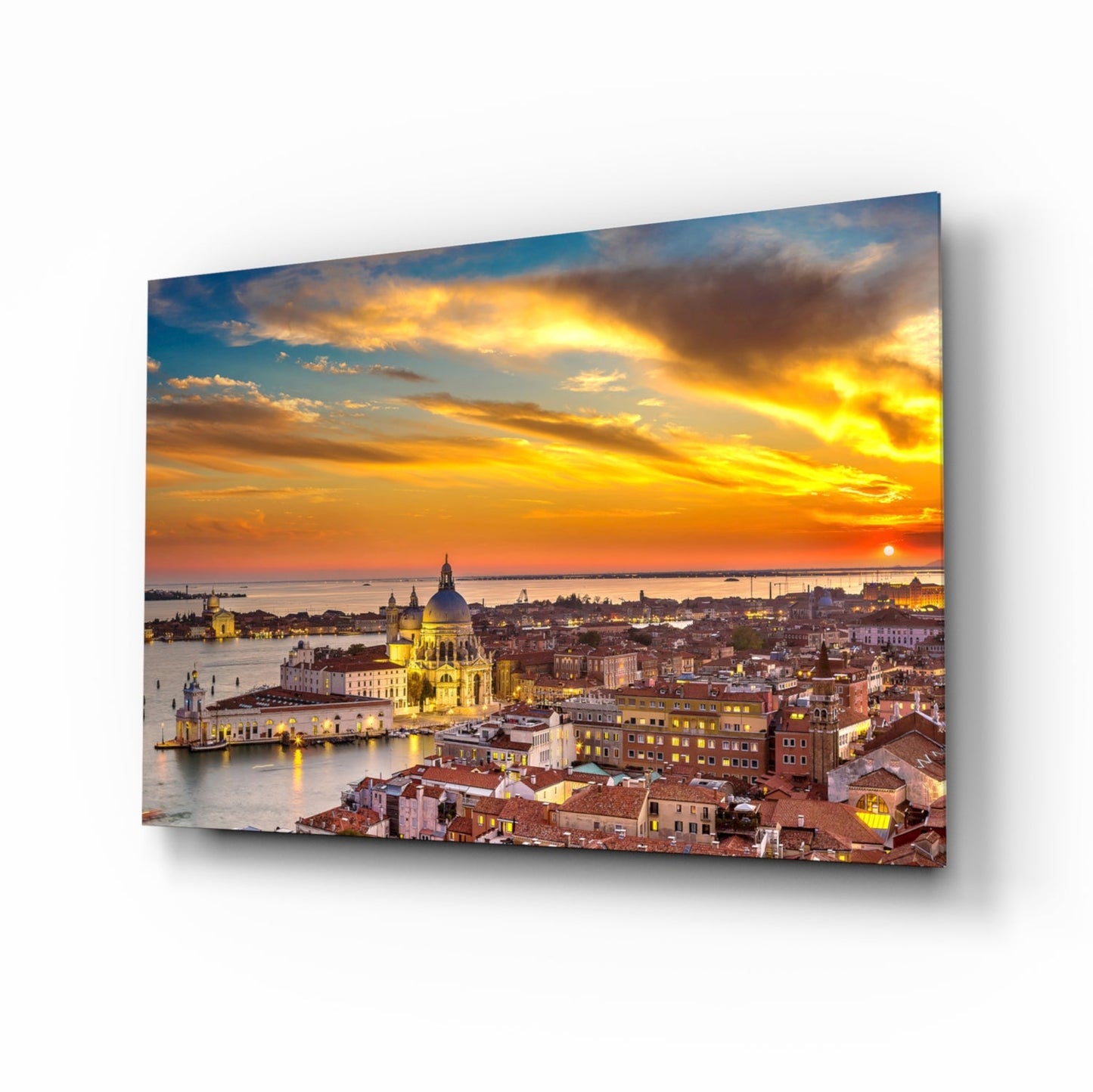 Glass wall art panel displaying Venice at sunset with illuminated Basilica di Santa Maria della Salute, golden sky, and waterfront buildings.