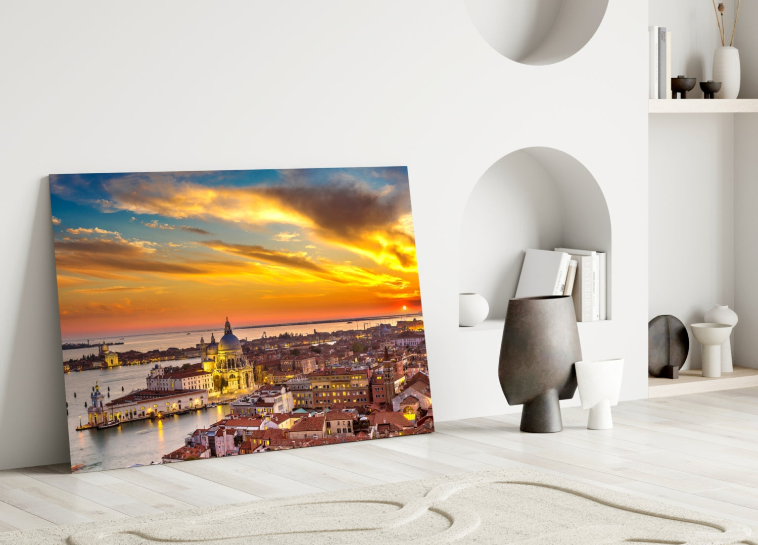 Glass wall art depicting Venice at golden sunset with illuminated basilica and waterfront, leaning against white wall beside decorative objects.