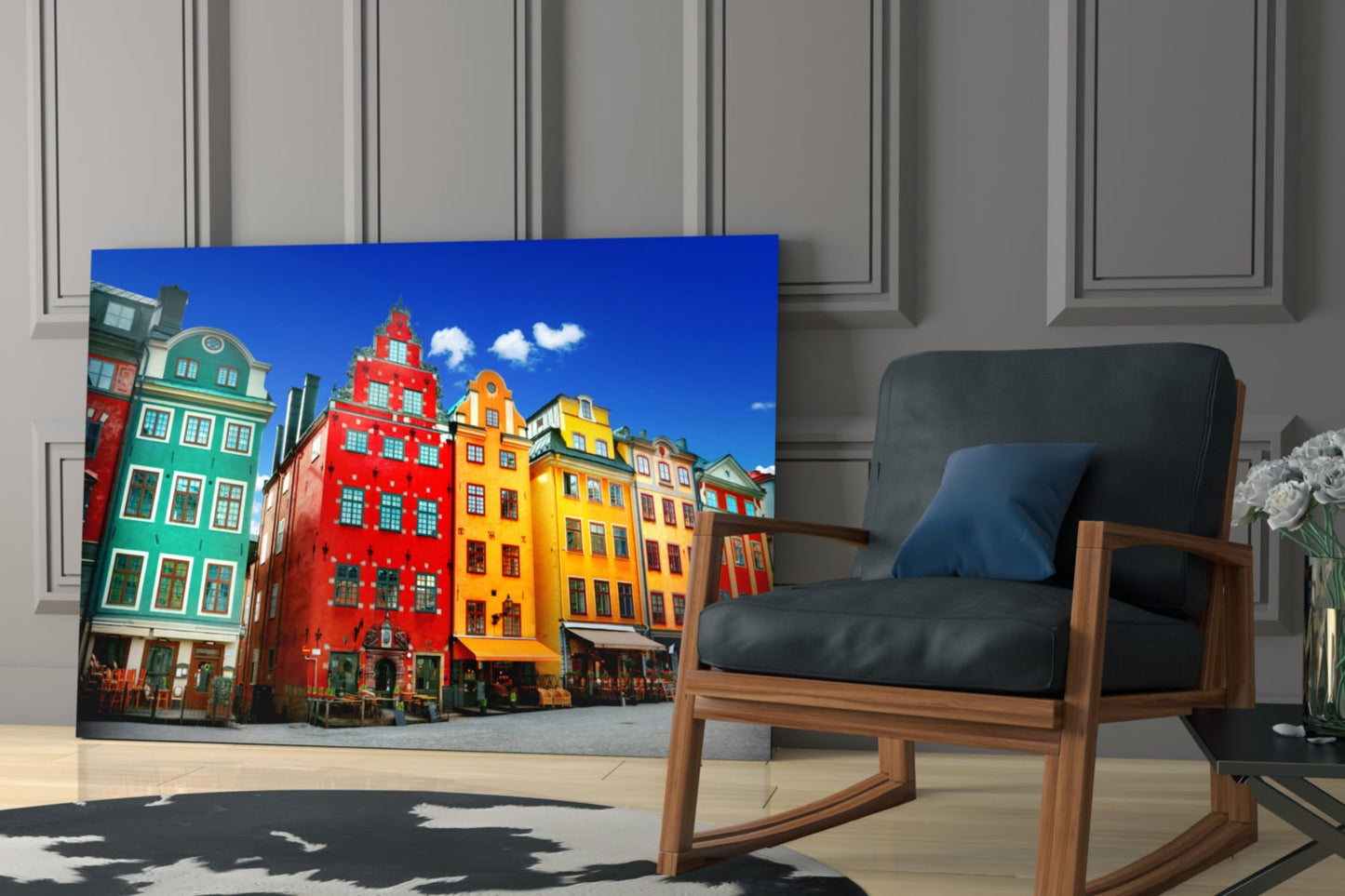 Glass wall art featuring colorful Stockholm buildings displayed in modern room with wooden chair and gray paneled walls.