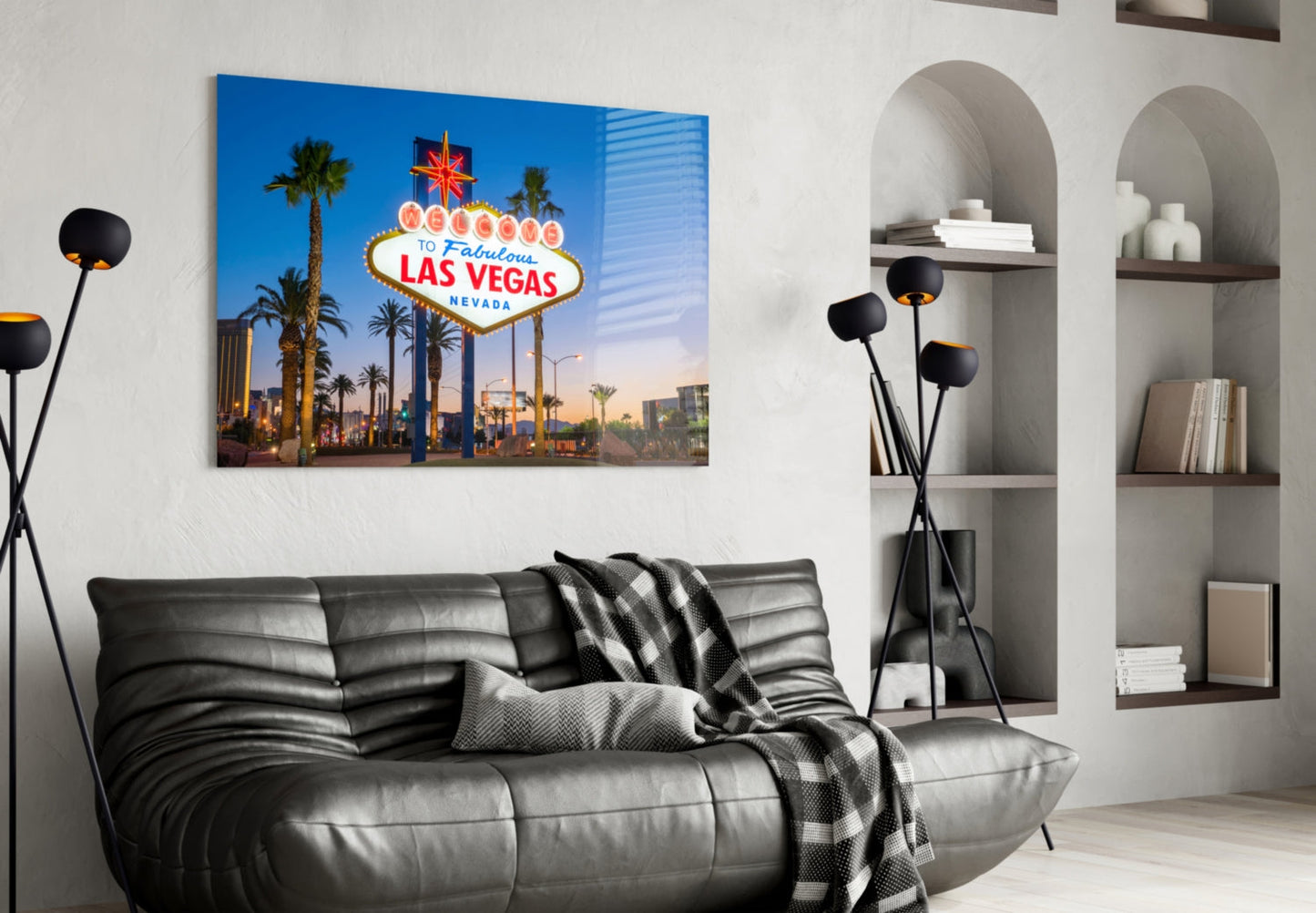 Las Vegas welcome sign glass wall art displayed above black leather sofa in modern living room interior.