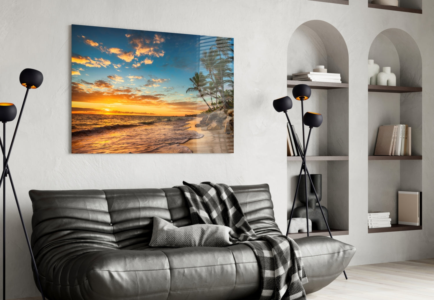 Beach Cruise glass wall art depicting golden sunset over ocean with palm trees, displayed above black leather sofa in modern living room.