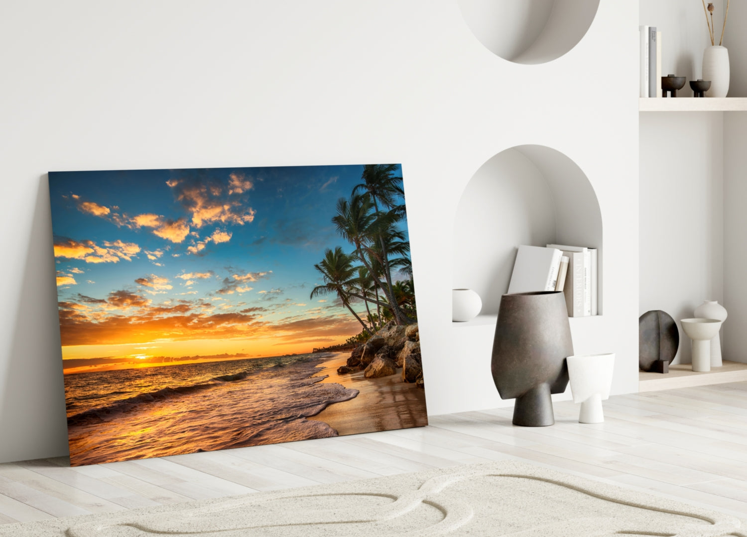 Beach Cruise Glass Wall Art leaning against white wall, displaying tropical sunset with golden sky, palm trees, and ocean waves.
