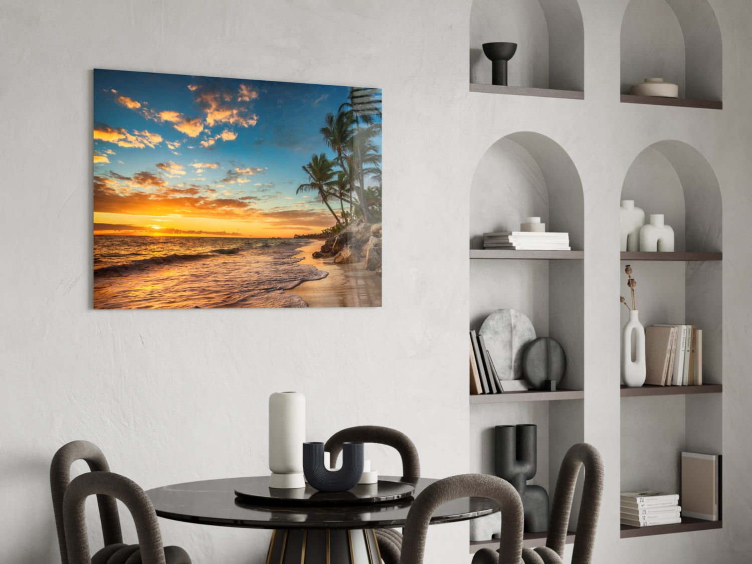 Beach Cruise Glass Wall Art displayed above a black round dining table, showing golden sunset over tropical coastline with palm trees.
