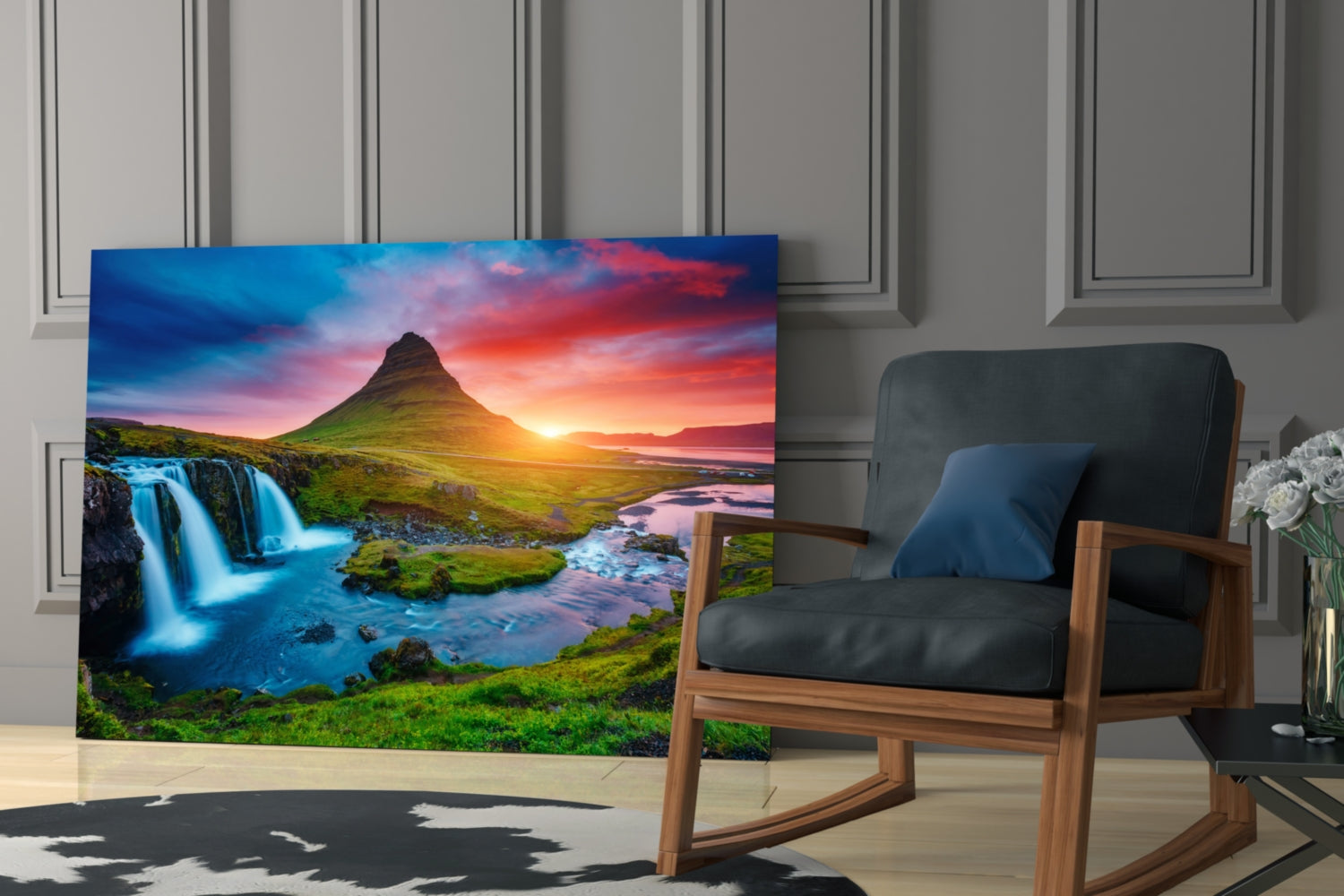 Glass wall art displaying Icelandic landscape with blue waterfall, green mountain, and sunset sky displayed in modern living room with wooden chair.