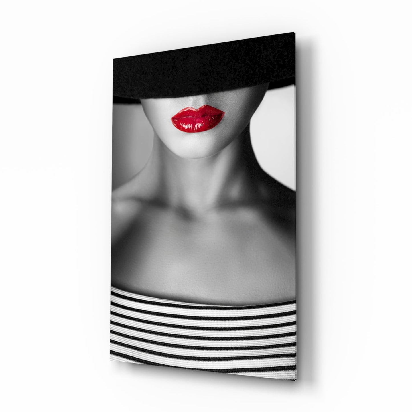 Glass wall art panel displayed at an angle showing a black and white portrait with red lips and striped neckline detail.