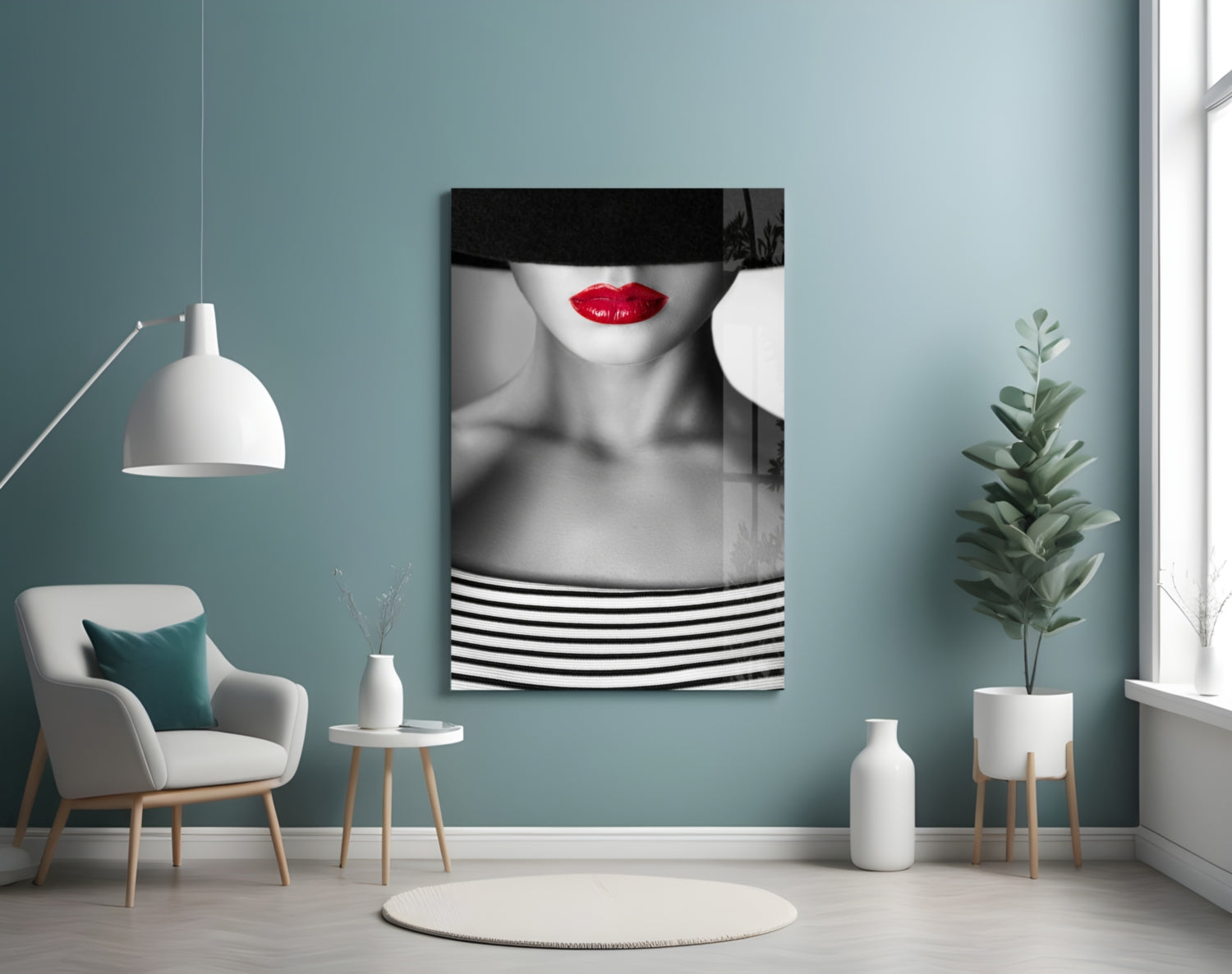 Black and white portrait with red lips and striped clothing displayed on turquoise wall above cream armchair with plant.