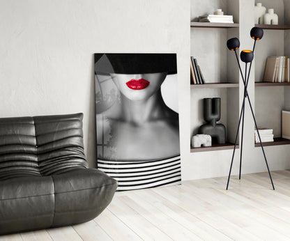 Modern living room featuring black leather chair, monochrome portrait with red lips on canvas, black tripod lamp, and wooden shelving unit.