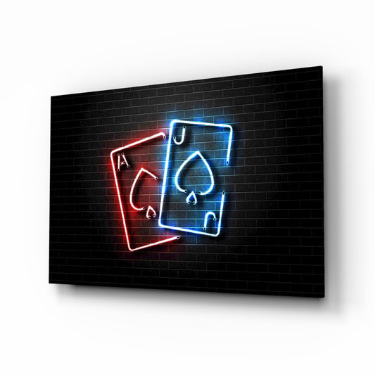 Neon glass wall art displaying red and blue playing cards with suit symbols on black brick background, angled perspective view.