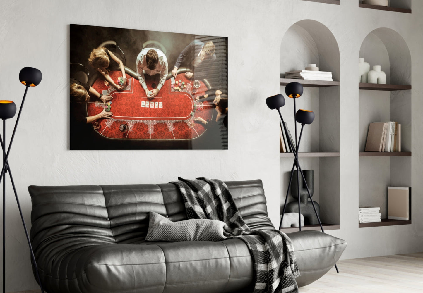 Black glass wall art featuring overhead view of people at red poker table displayed above gray leather sofa in modern living room.