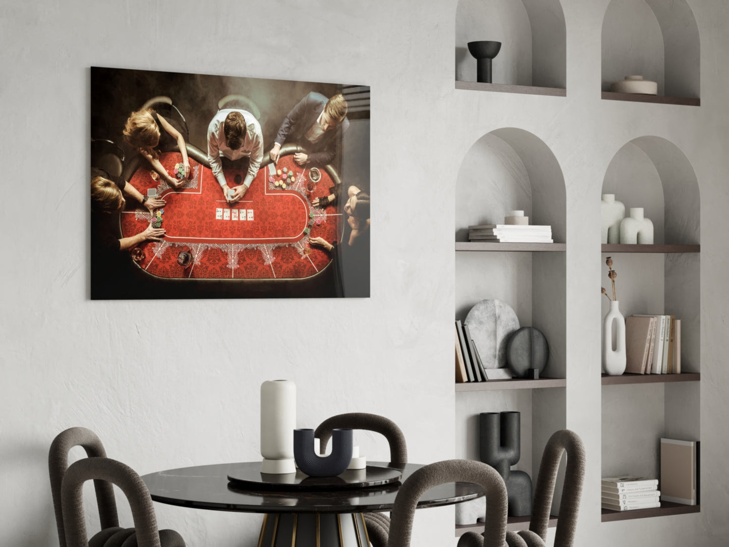 Glass wall art depicting overhead view of people in red traditional dress seated at red patterned table, displayed above black dining table in modern interior.