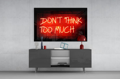 Red neon "Don't Think Too Much" sign displayed on wall above gray media console with decorative items.