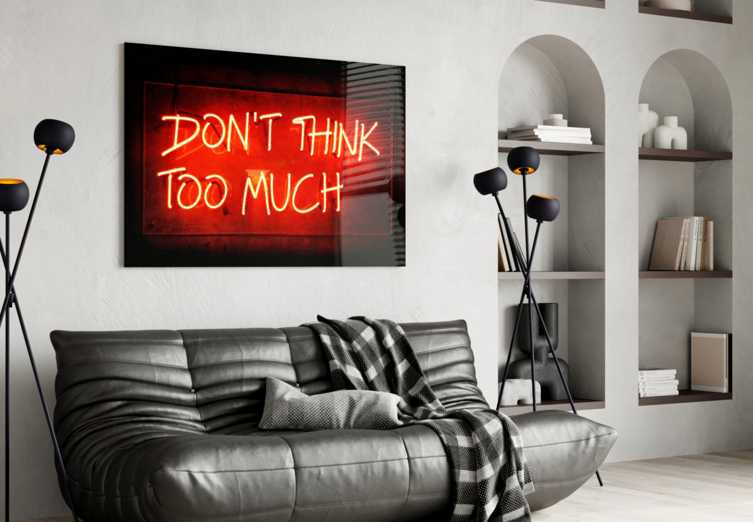 Red neon "Don't Think Too Much" glass wall art displayed above black leather sofa in modern living room with shelving.