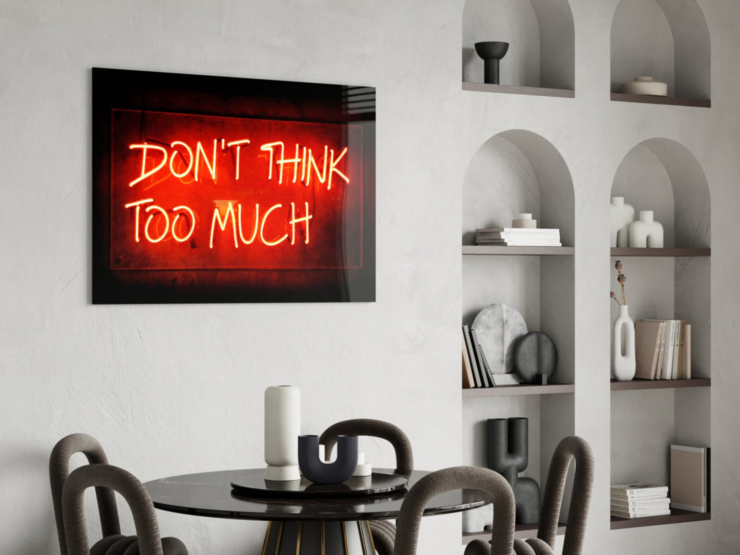 Red neon sign reading "DON'T THINK TOO MUCH" displayed above a dining table with chairs and built-in shelving.
