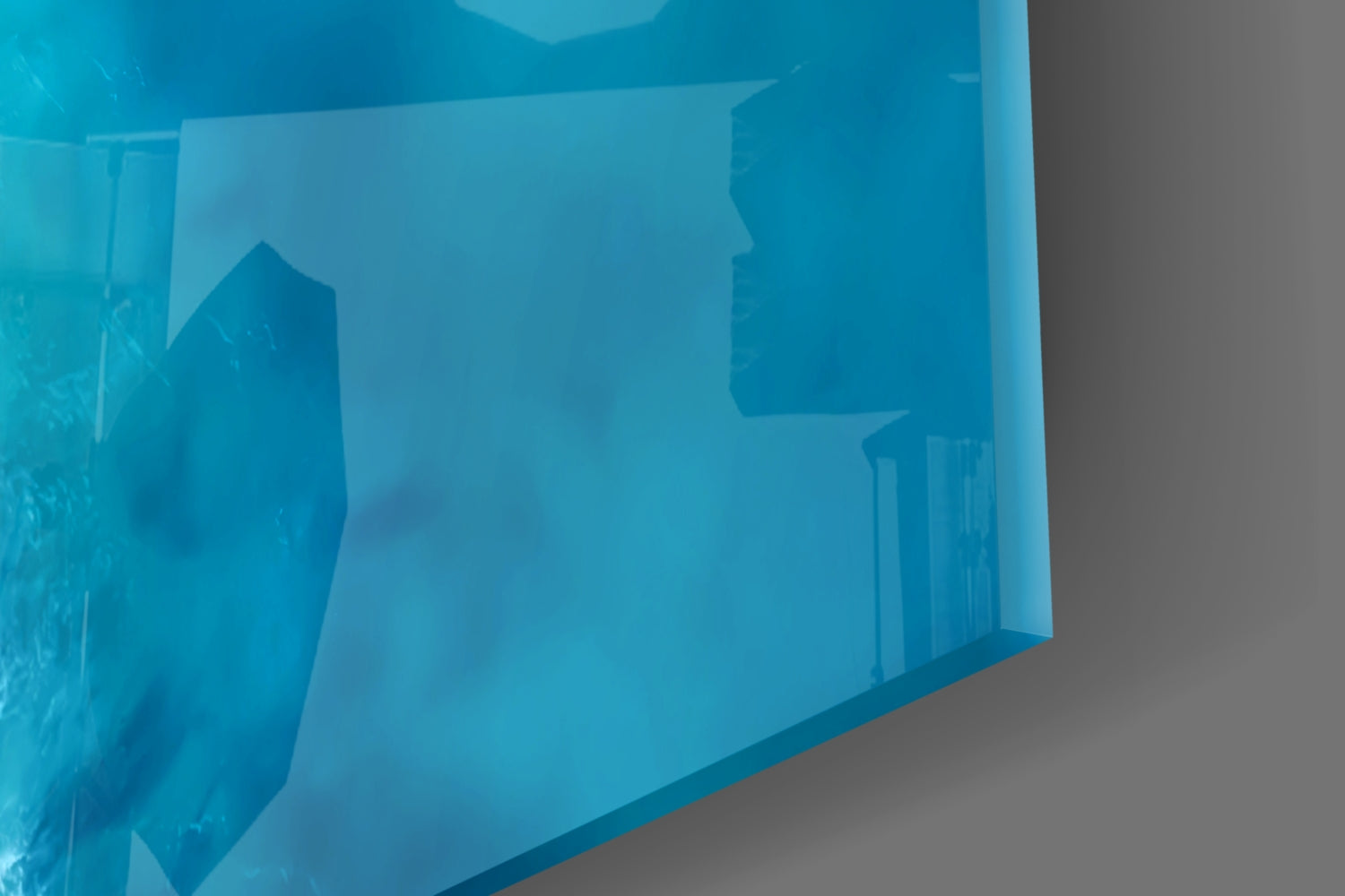 Angled side view of blue glass wall art panel showing layered architectural silhouettes against turquoise gradient background.