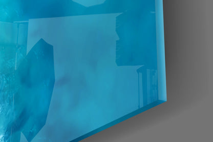 Angled side view of blue glass wall art panel showing layered architectural silhouettes against turquoise gradient background.