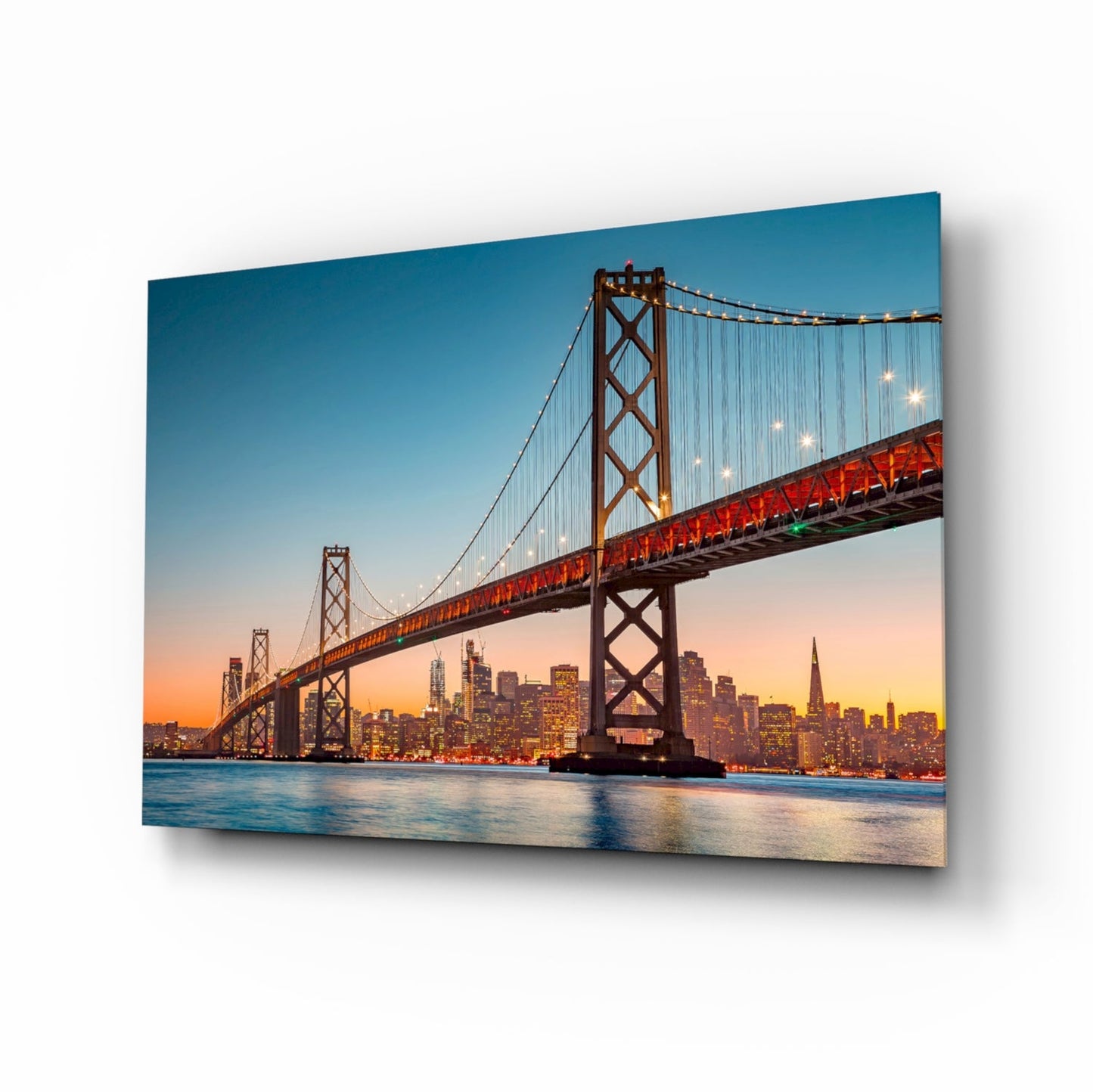 Bay Bridge at twilight with illuminated San Francisco skyline, displayed as framed glass wall art against white background.