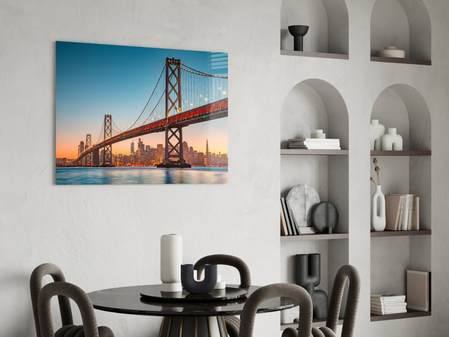 San Francisco Bay Bridge glass wall art hanging above black dining table in modern interior with white shelving.