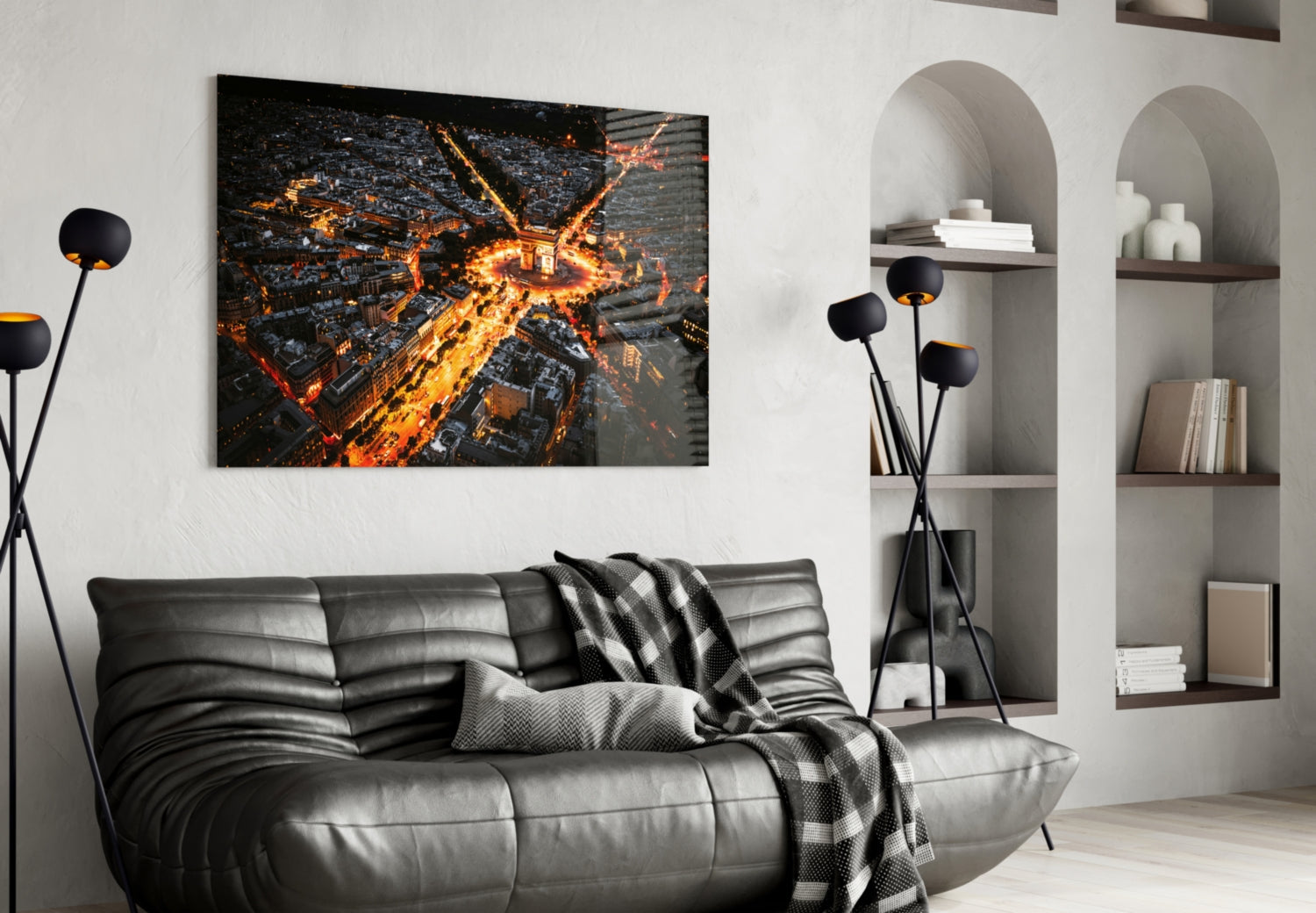 Glass wall art depicting an aerial nighttime view of illuminated Paris streets arranged in a radial pattern, displayed above a black leather sofa in a modern living room.