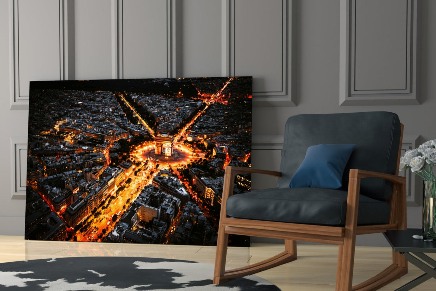 Aerial nighttime photograph of illuminated Paris streets radiating from Arc de Triomphe displayed as black glass wall art in modern living room with wooden chair.