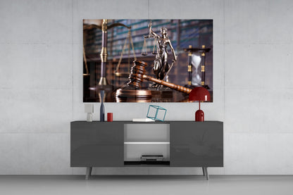 Glass wall art depicting a wooden gavel and Lady Justice statue displayed above a gray media console in a modern interior setting.