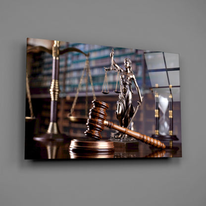 Wooden gavel on brass base with scales of justice and Lady Justice statue blurred in background, displayed on glass wall art panel.