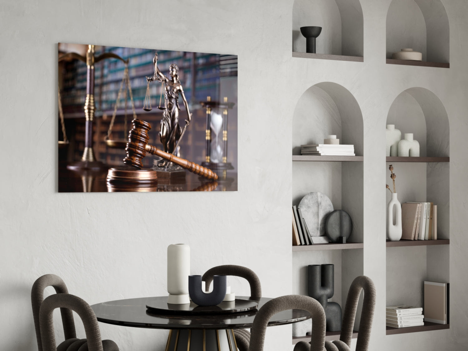Glass wall art depicting a wooden gavel and Lady Justice statue displayed above a black dining table with grey chairs.