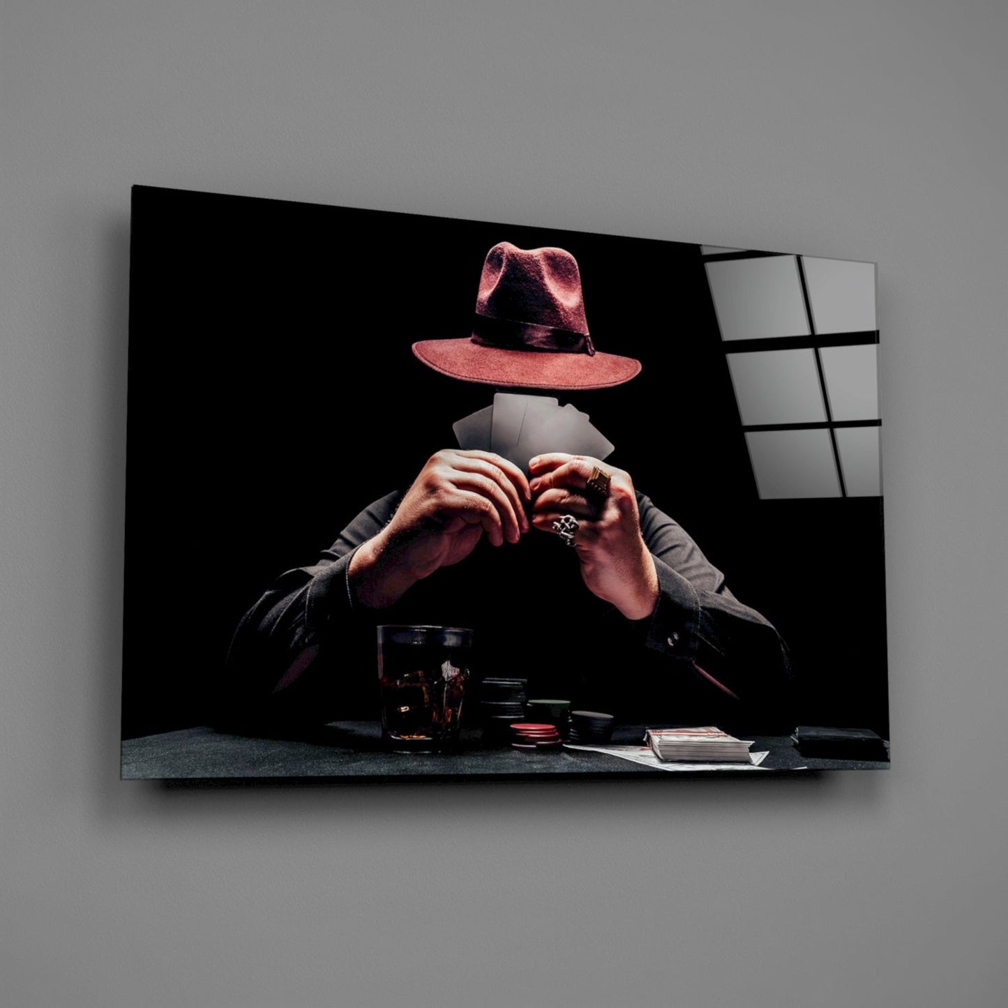 Glass wall art displaying a figure in a pink fedora and dark jacket making a heart shape with their hands over a table with poker chips and cards against black background.