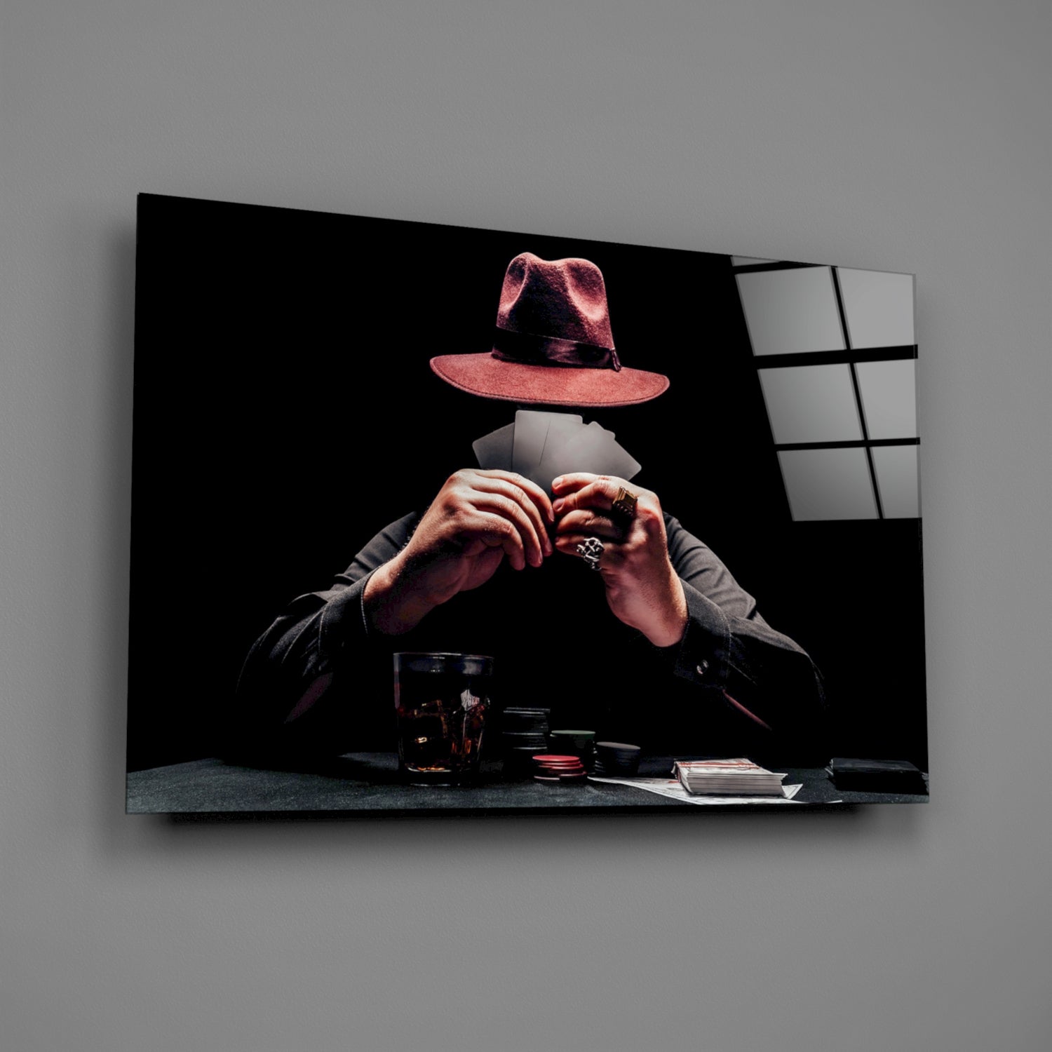 Glass wall art displaying a figure in a pink fedora and dark jacket making a heart shape with their hands over a table with poker chips and cards against black background.