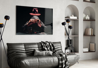 Black glass wall art depicting a figure in a red hat making a heart hand gesture, displayed above a gray leather sofa in a modern living room.