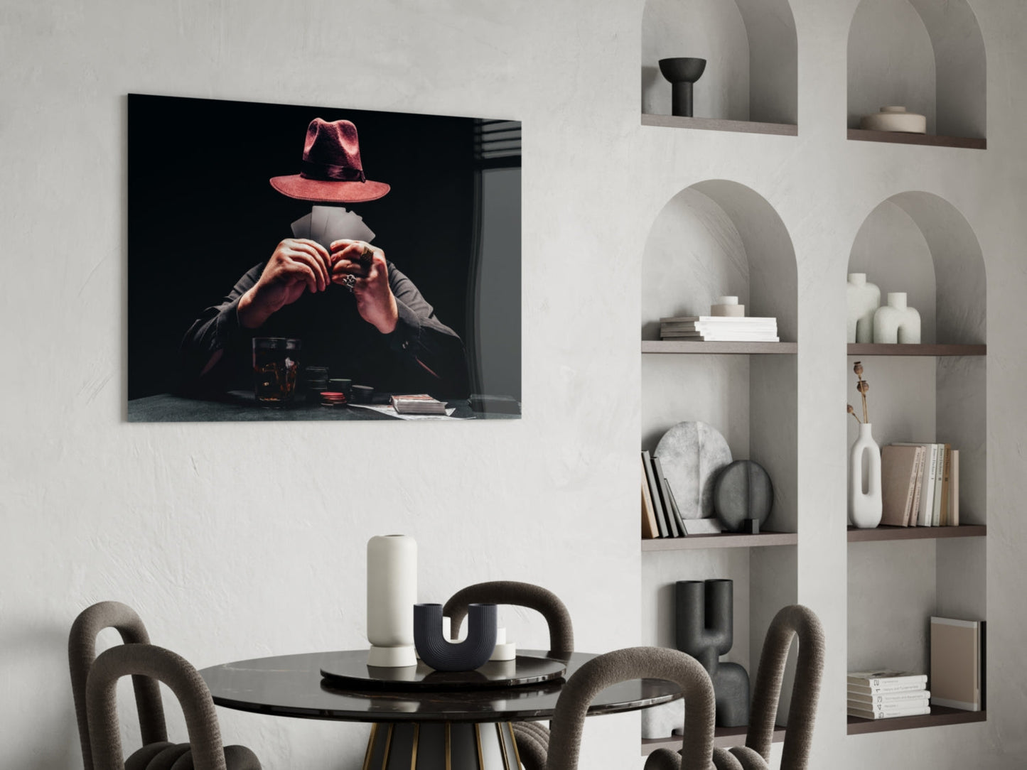 Glass wall art displaying a figure in a red hat and hands making a heart gesture against black background, hung above a round black dining table.