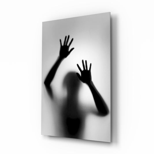 Angled view of frosted glass panel displaying blurred silhouette of figure with two raised hands against white background.