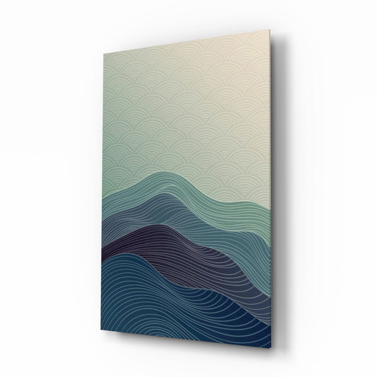 Angled perspective of rectangular glass wall art featuring layered wave line patterns transitioning from cream to teal and deep blue.