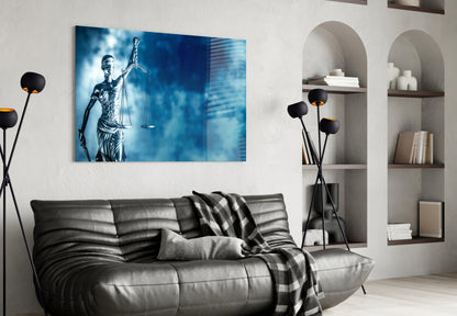 Blue glass wall art depicting Lady Justice holding scales displayed above a black leather sofa in modern living room interior.