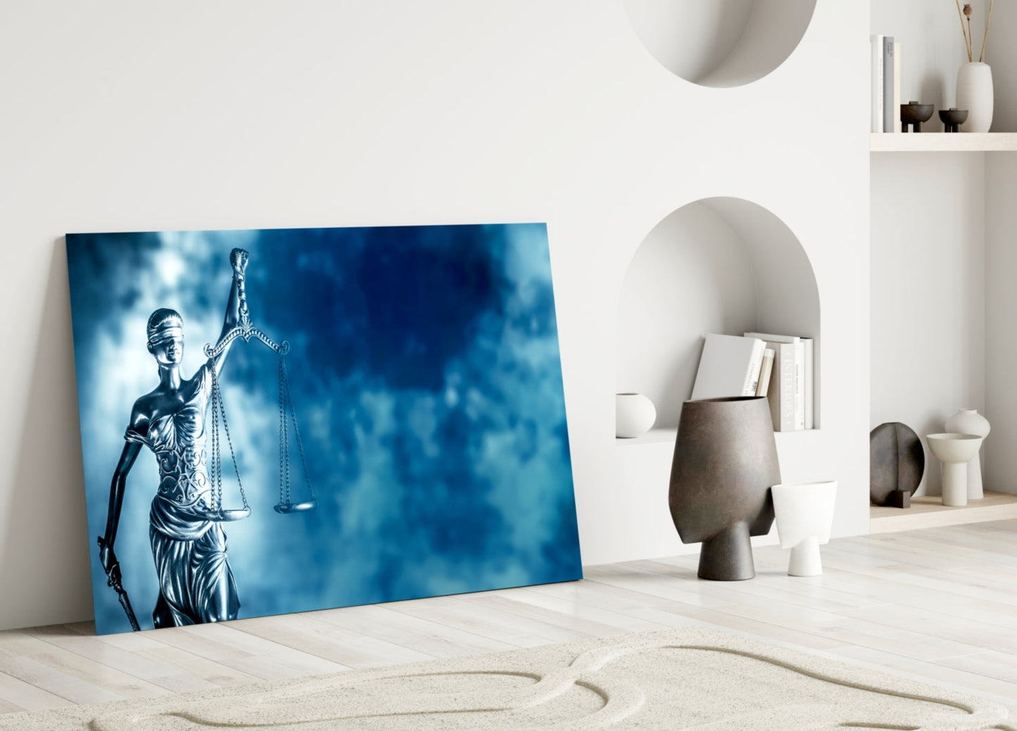 Blue glass wall art depicting Lady Justice statue leaning against white wall in minimalist interior setting.