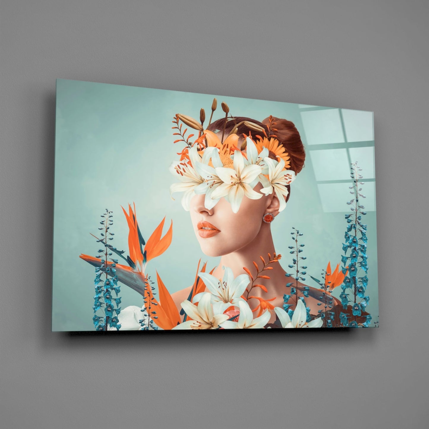 Glass wall art displaying a woman's profile with reddish-brown hair, white and orange flowers covering her eyes, surrounded by blue-green foliage against a pale turquoise background.