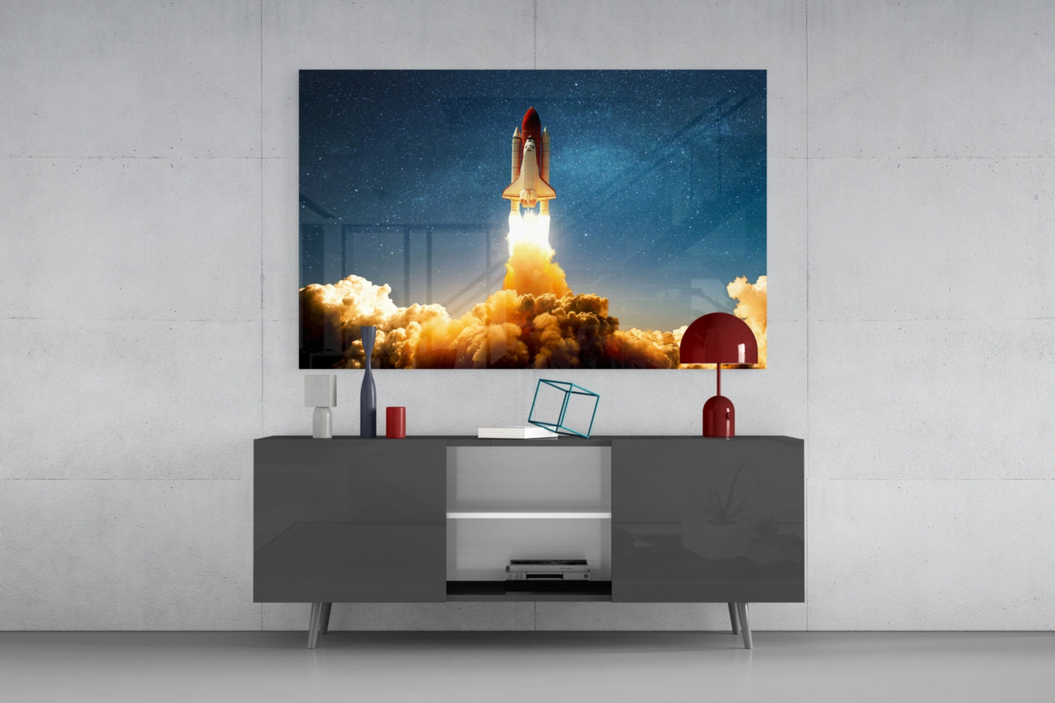 Glass wall art depicting a space shuttle launching through orange clouds against a starry blue sky, mounted above a dark gray media console.