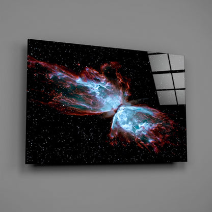 Modern glass wall art displaying a nebula with blue and red cosmic gas clouds against a starry black background, mounted at an angle.