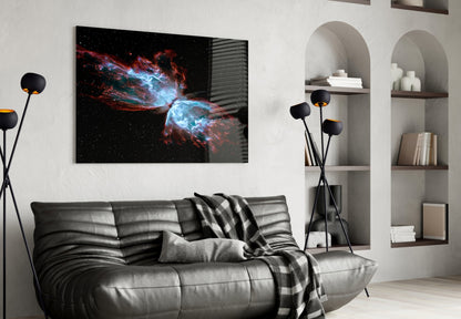Space Red Glass Wall Art displaying a red and blue nebula against black starfield, hung above a black leather sofa in a modern living room.