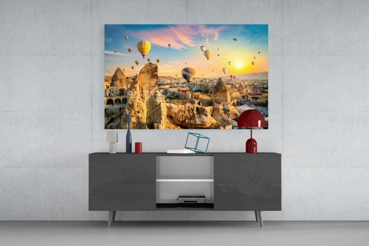 Glass wall art displaying Cappadocia hot air balloons and rock formations at sunset, mounted above dark gray media console.