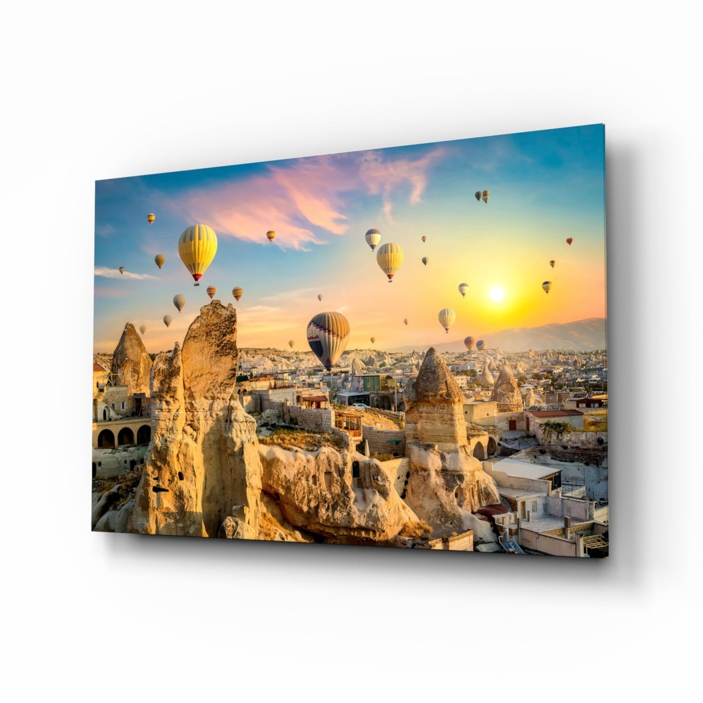 Hot air balloons float above Cappadocia's fairy chimneys at sunset, displayed on angled glass wall art.